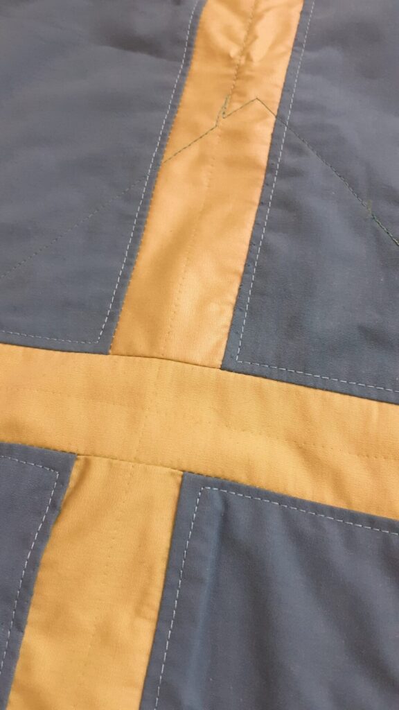The back of the same small quilt with ripped stitches visible. Color of small strips seems to be different from the top but was identical. 