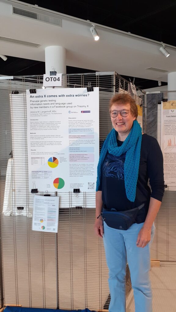 Jessica standing in front of her poster at the congress venue in Padova, Italy. She is blond and wears blue clothes. The poster is on https://www.xxs2info.nl/padua2025/